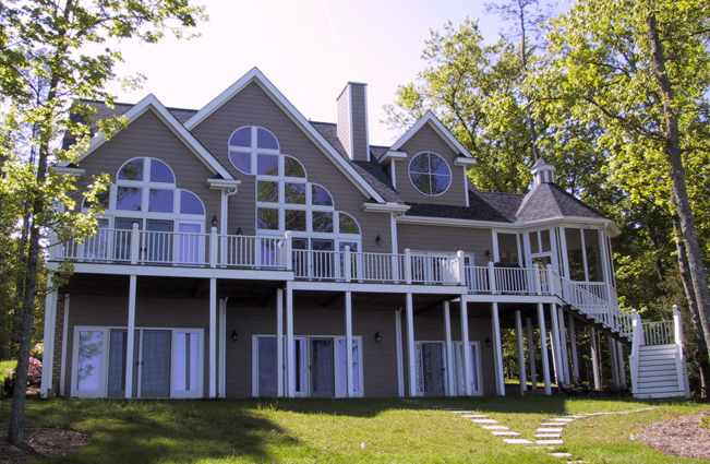 Lakeside home with arched windows and wraparound decks