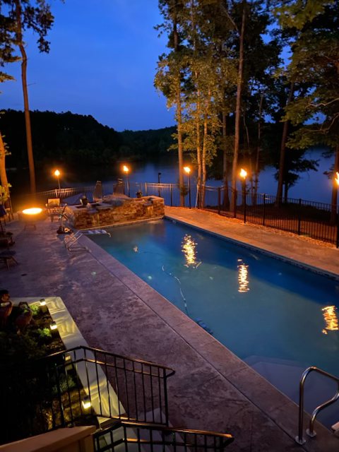Pool at dusk with torch light and the lake beyond