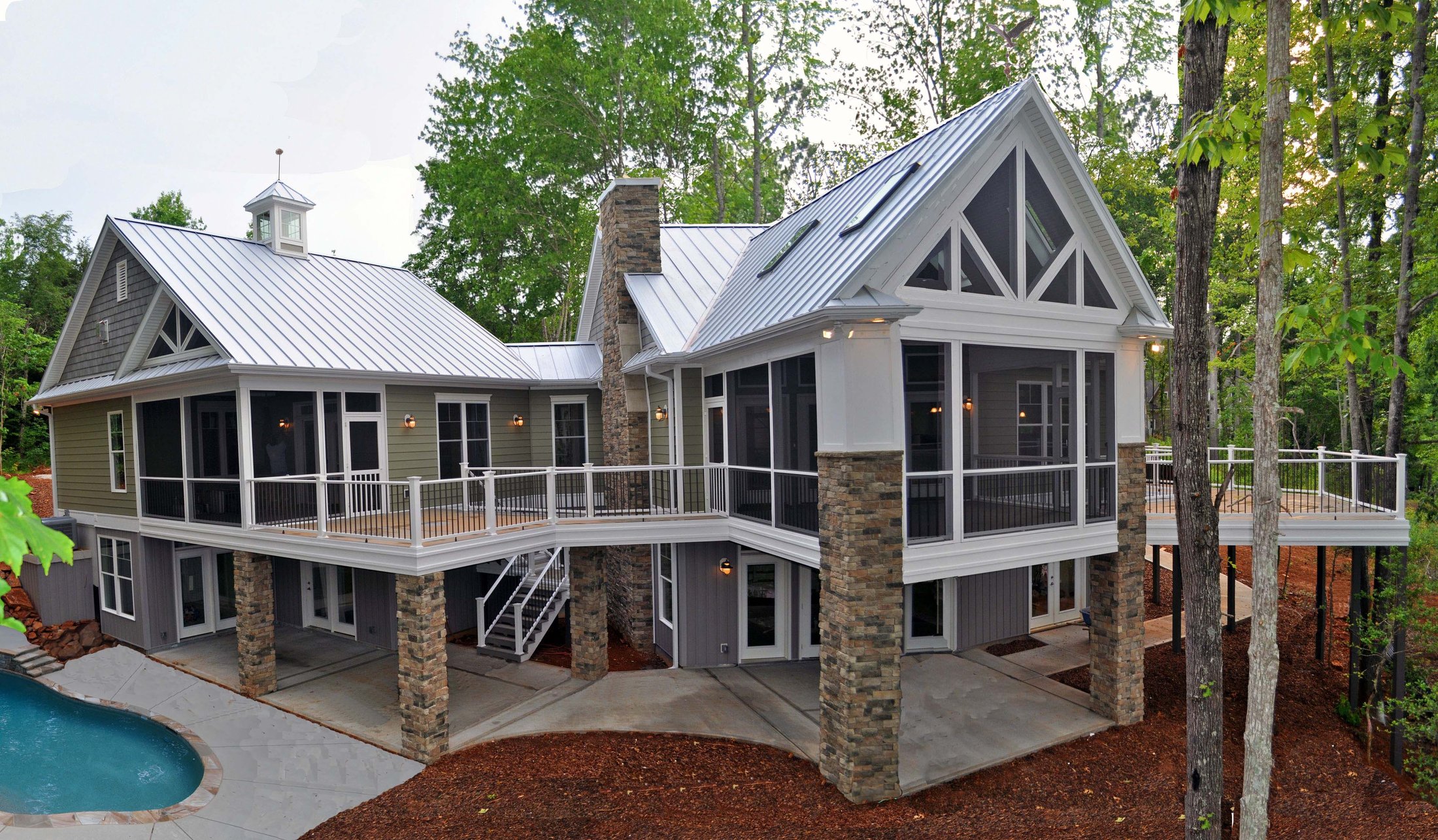 Lake house with screened porches, stone piers, and a pool