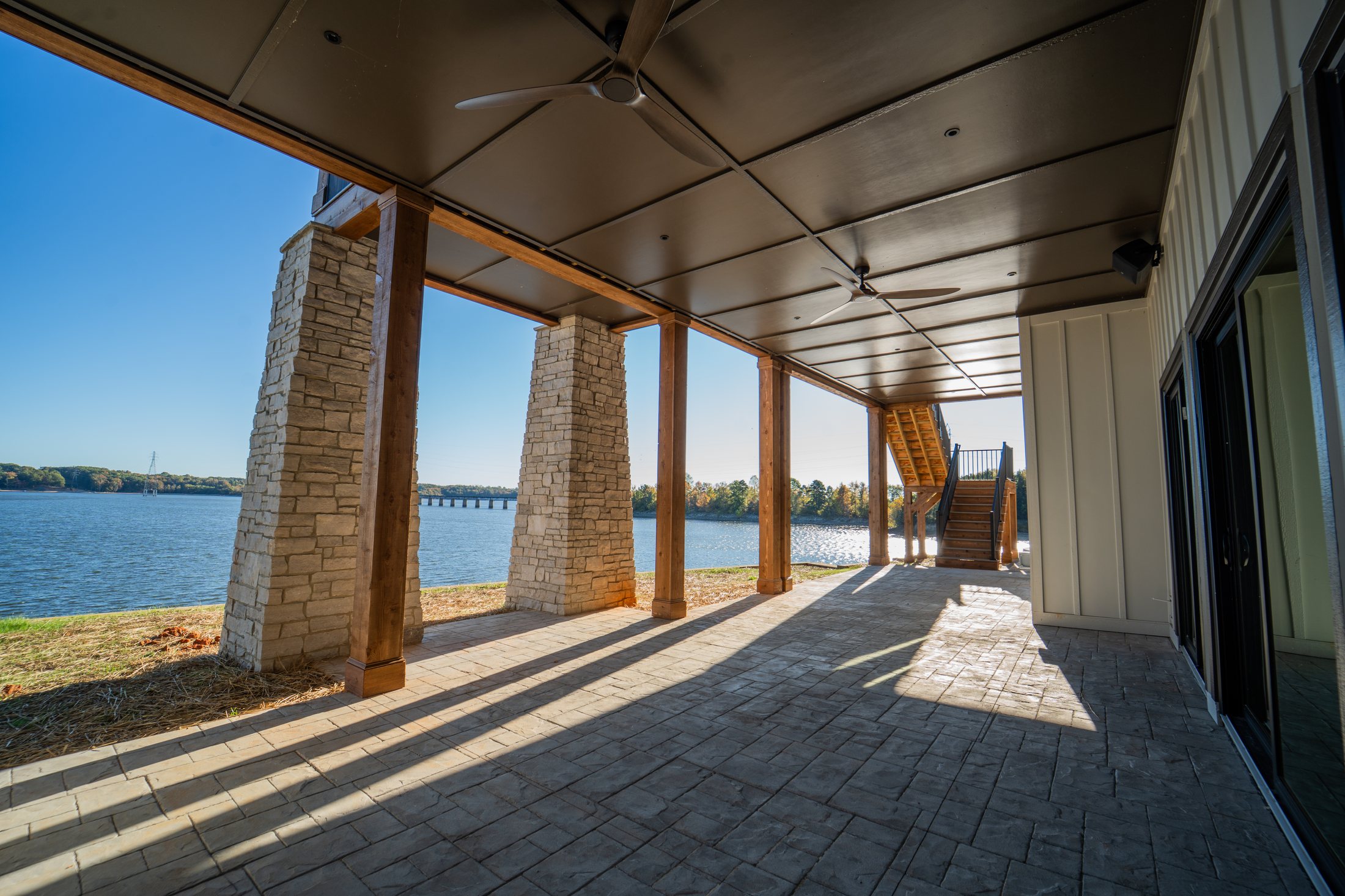 Covered lake porch with stone piers looking toward the dam